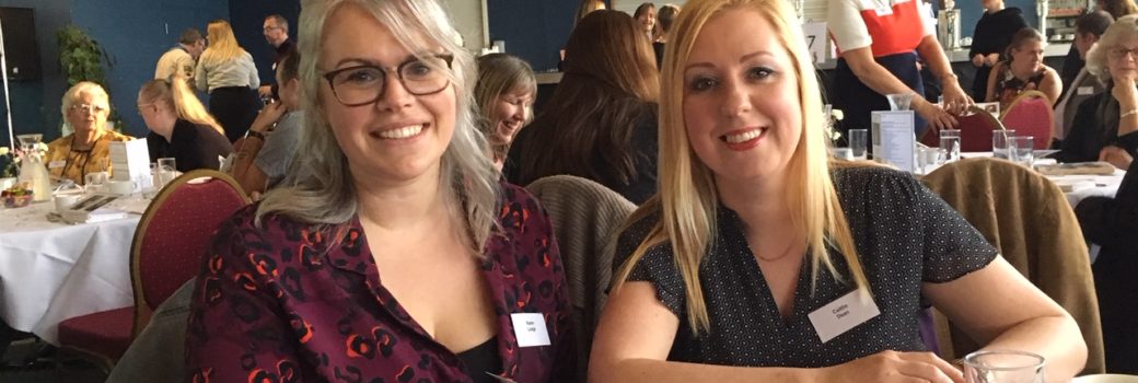 An image of two blonde haired females attending a conference
