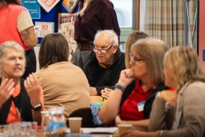 A picture of people sat around a table at a conference