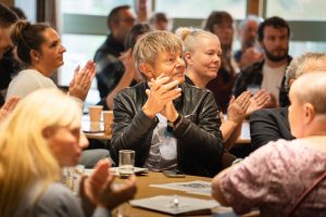 An image of people sat around a table at a conference