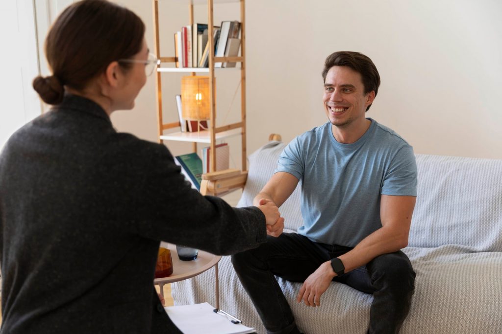 An image of a female psychologist shaking hands with a male client following a counselling session about mental health