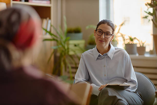 An image of a woman who is a counsellor undertaking a therapy session with another person who we can only see the back of