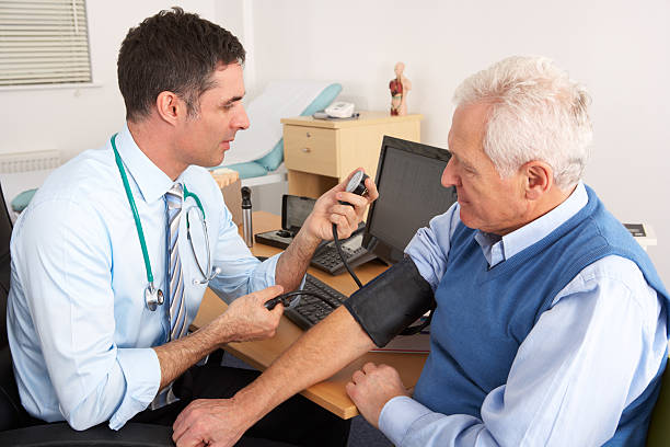 An image of a doctor taking an older man's blood pressure in surgery room having a check up