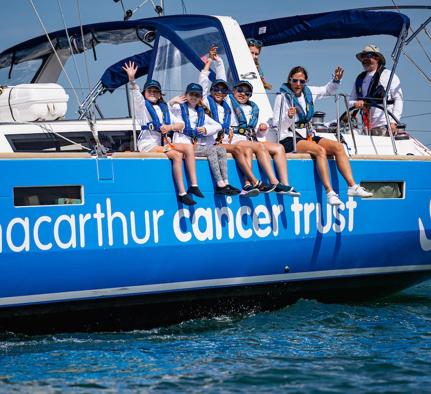 An image of four young people sat on the side of a boat with the logo Ellen Macarthur Cancer Trust