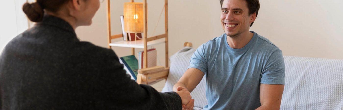 An image of a female psychologist shaking hands with a male client following a counselling session about mental health